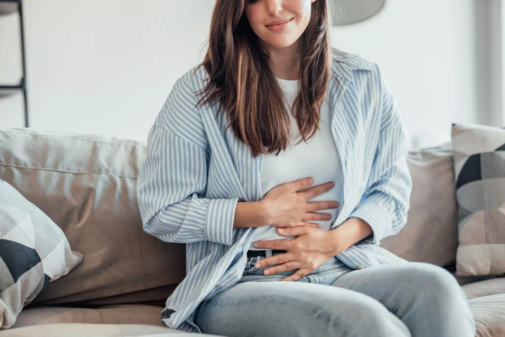 A woman experiencing a Mild stomach discomfort
due to side effect of taking a GLP-1 Weight Loss Medication